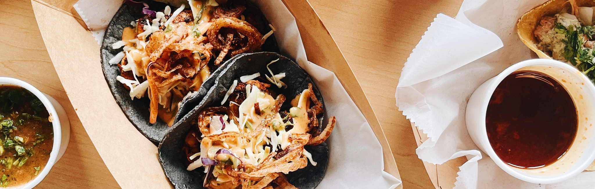 Tacos and salsa sit on a wooden table